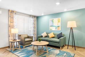 A living room with a sofa, two armchairs, a coffee table, a floor lamp, and a painting on the wall.