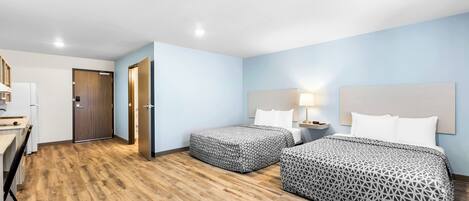 Habitación de hotel con dos camas, un escritorio y kitchenette.
