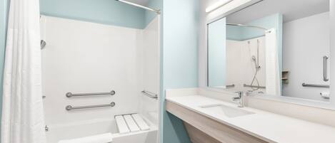 A modern bathroom with a glass-enclosed shower, a white sink, and a large mirror.