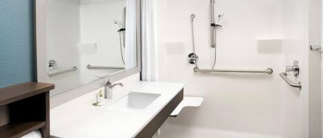 A modern bathroom with a white sink, mirror, and bathtub. There are grab bars installed for safety.