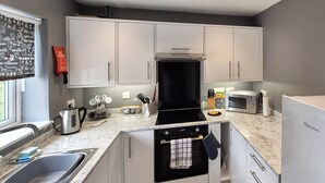 Une cuisine moderne avec des meubles blancs, un four noir, un four à micro-ondes et un évier.