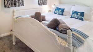 Un lit bien fait, avec une couverture à rayures, deux oreillers et une serviette enroulée.