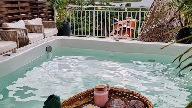 A rooftop pool with a sunset view, wicker baskets with food and drinks, and outdoor seating. - Villa Verde Bangalô - Garopaba - SC (Garopaba)