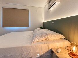 Quarto de hotel moderno com cama, abajur e aparelho de ar condicionado.
