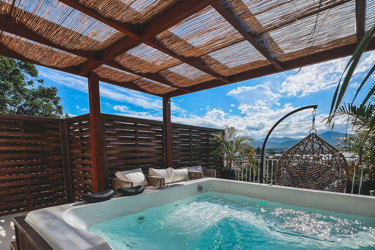 A hot tub with a wooden deck and a view of the sky.