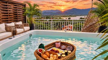 Piscina en la azotea con vistas al atardecer, mobiliario de mimbre y una cesta de frutas.