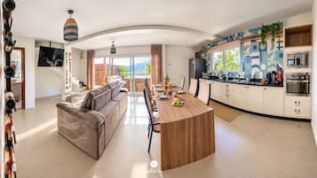 Cocina moderna con una isla central, zona de comedor con sofá y un amplio ventanal con vistas.