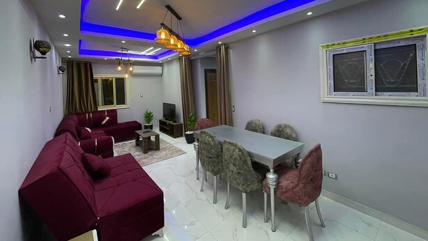 Una sala de estar moderna con un sofá seccional, una mesa de comedor con sillas y un televisor.
