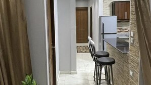 Una cocina moderna con encimera de mármol, refrigerador y una barra con taburetes.