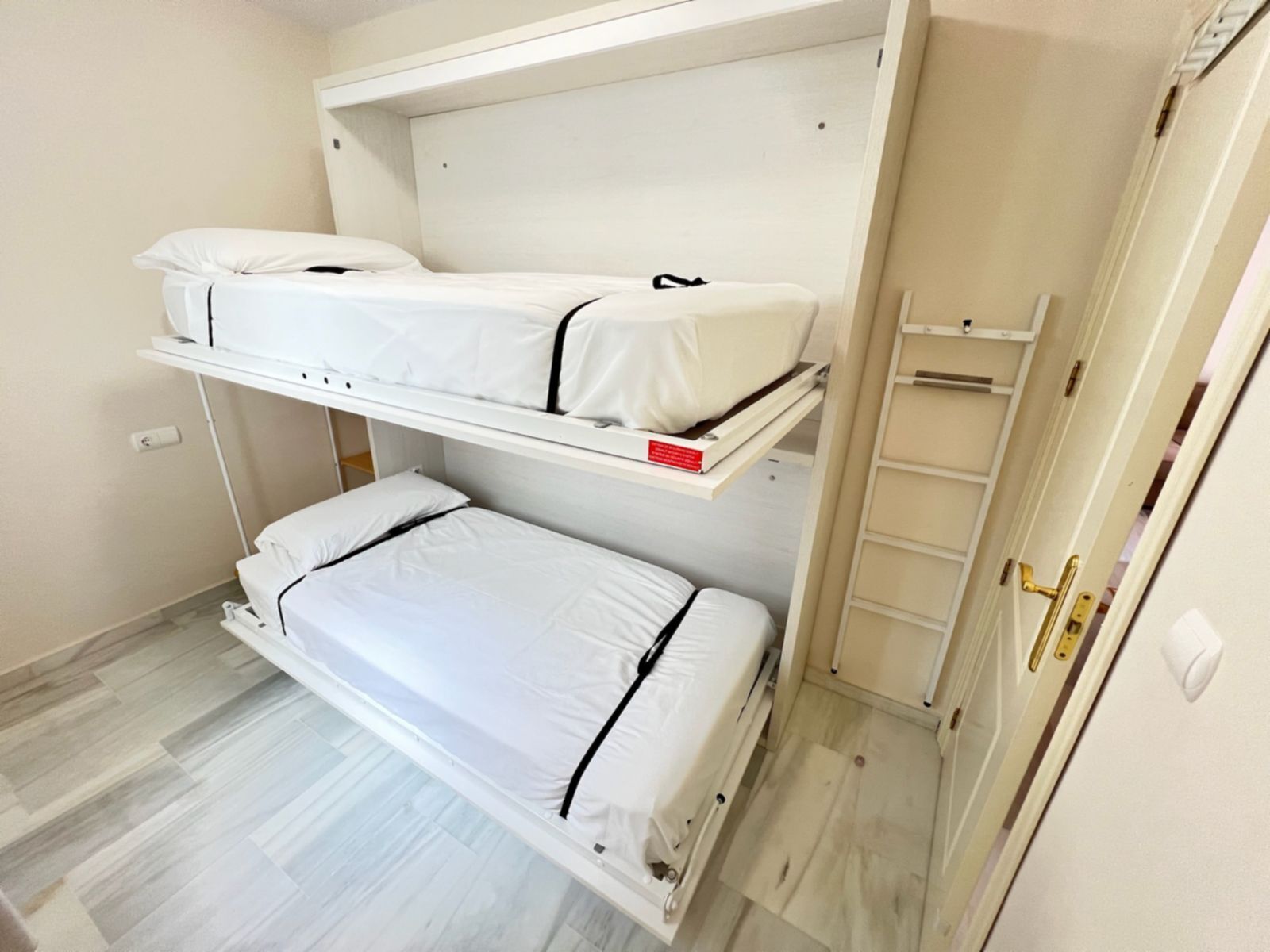 A bunk bed room with a ladder and a wardrobe.