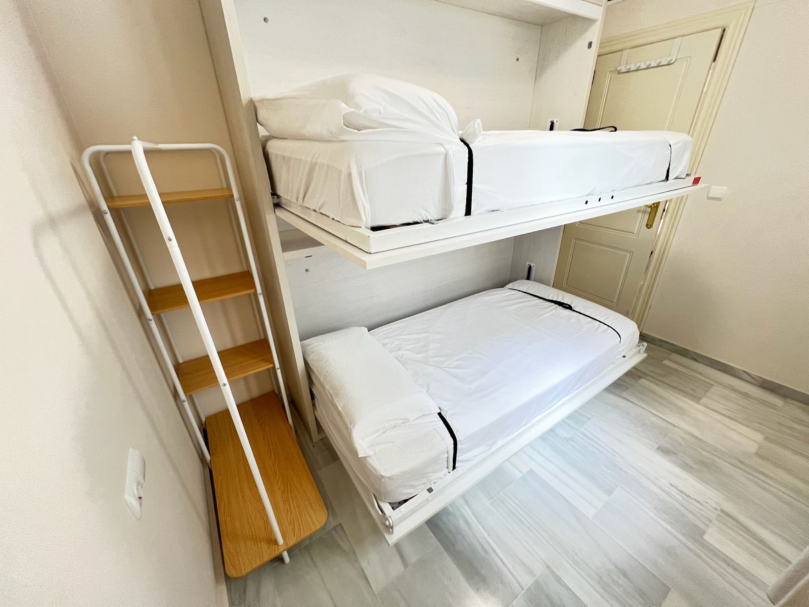 A bunk bed room with a ladder and a door.