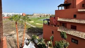 A view of a golf course with a red building in the foreground. - PUSHE Playa Granada Beach & Golf 17 (Motril)
