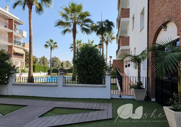 A courtyard with a pool, palm trees, and a wooden deck.