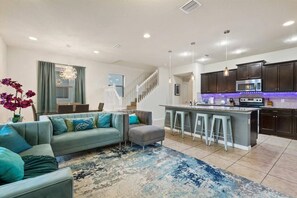 Relax in a spacious living area with a sofa, ottoman, and bar with stools. Enjoy a fully equipped kitchen with a stainless steel oven and microwave.
