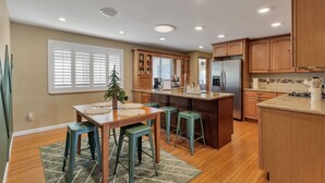 Una cocina moderna con armarios de madera, una isla central, taburetes de bar y una mesa de comedor.