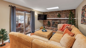 Una sala de estar con sofá, reposapiés y chimenea.