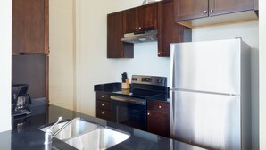 Una cocina moderna con armarios de madera oscura, un refrigerador de acero inoxidable, una estufa negra y una cafetera.