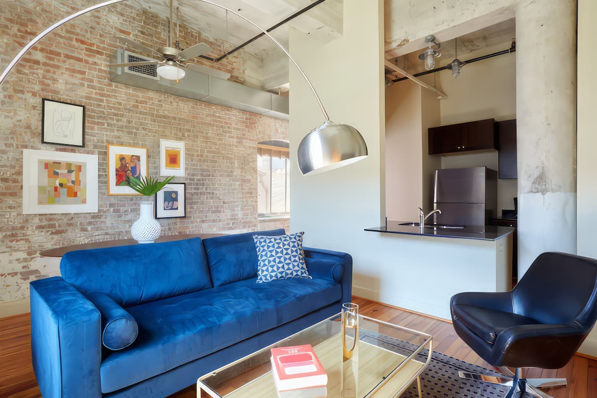 Un salon moderne avec un canapé bleu, un fauteuil noir et une table basse en verre.