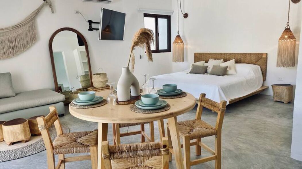 Ein gemütliches Schlafzimmer mit Bett, Nachttisch mit Dekoration und rundem Esstisch mit Stühlen.