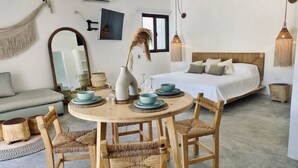 A cozy bedroom with a bed, bedside table with decorative items, and a round dining table with chairs. - Casa Macay Tulum (Tulum)