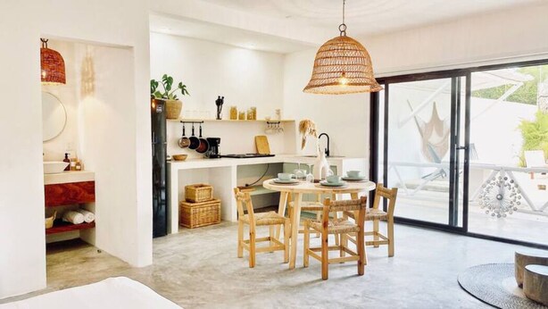 A modern kitchen with a dining area, large windows, and a view of the outdoors. - Casa Macay Tulum (Tulum)