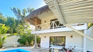 A two-story building with a pool, a covered balcony, and a thatched roof. - Casa Macay Tulum (Tulum)
