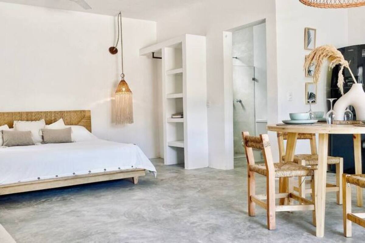 Une chambre à coucher comprenant un lit, des tables de chevet et un coin repas avec des chaises et une table.