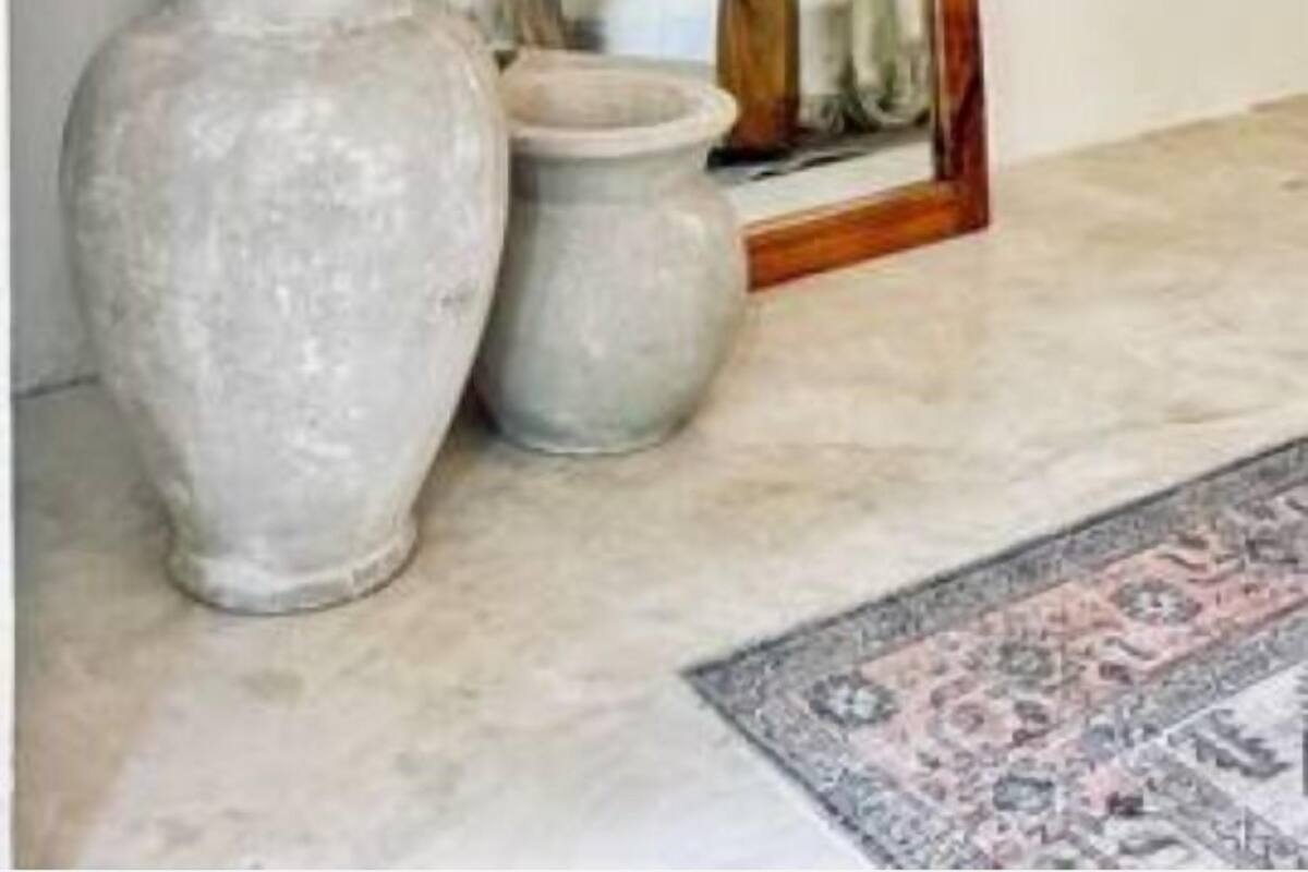 Une pièce avec un grand miroir, deux vases et un tapis.