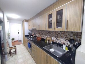 Een keuken met houten kastjes, een zwart aanrecht en een betegelde spatwand.