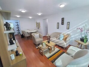 Een moderne woonkamer met een bank, fauteuils, een salontafel en een eethoek met een tafel en stoelen.
