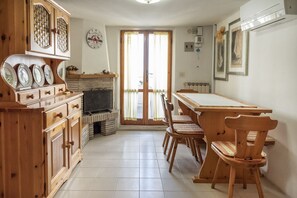 A kitchen with wooden cabinets, a dining table, chairs, a fireplace, and a view through the glass doors.