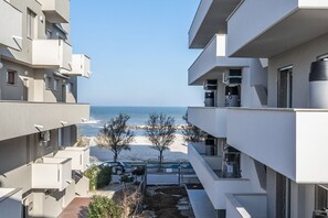 A modern apartment building with balconies overlooking a beach.