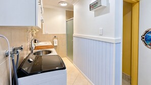 A compact bathroom with a washing machine, a sink, and a shower.