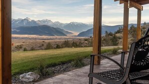 Una pérgola de madera con un banco que da a un paisaje montañoso.