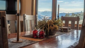 Una mesa de comedor con vistas a montañas, velas y una planta en maceta.