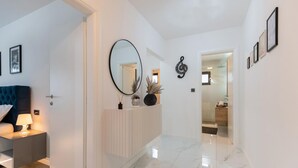 Un couloir moderne avec une porte blanche, un miroir rond et une horloge au mur.