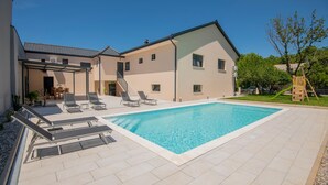 Un immeuble résidentiel moderne doté d’une piscine, d’un espace extérieur aménagé et d’un escalier menant à un patio couvert.
