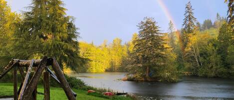 A wooden swing set near a lake with a rainbow in the background.