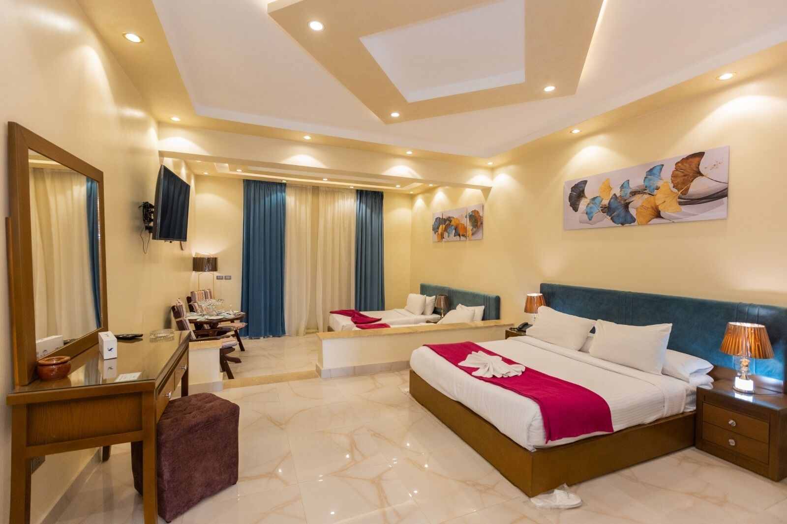 Habitación de hotel con una cama grande, un escritorio, una silla, un espejo y un televisor.