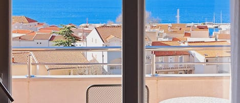 A balcony with a view of the sea and buildings.