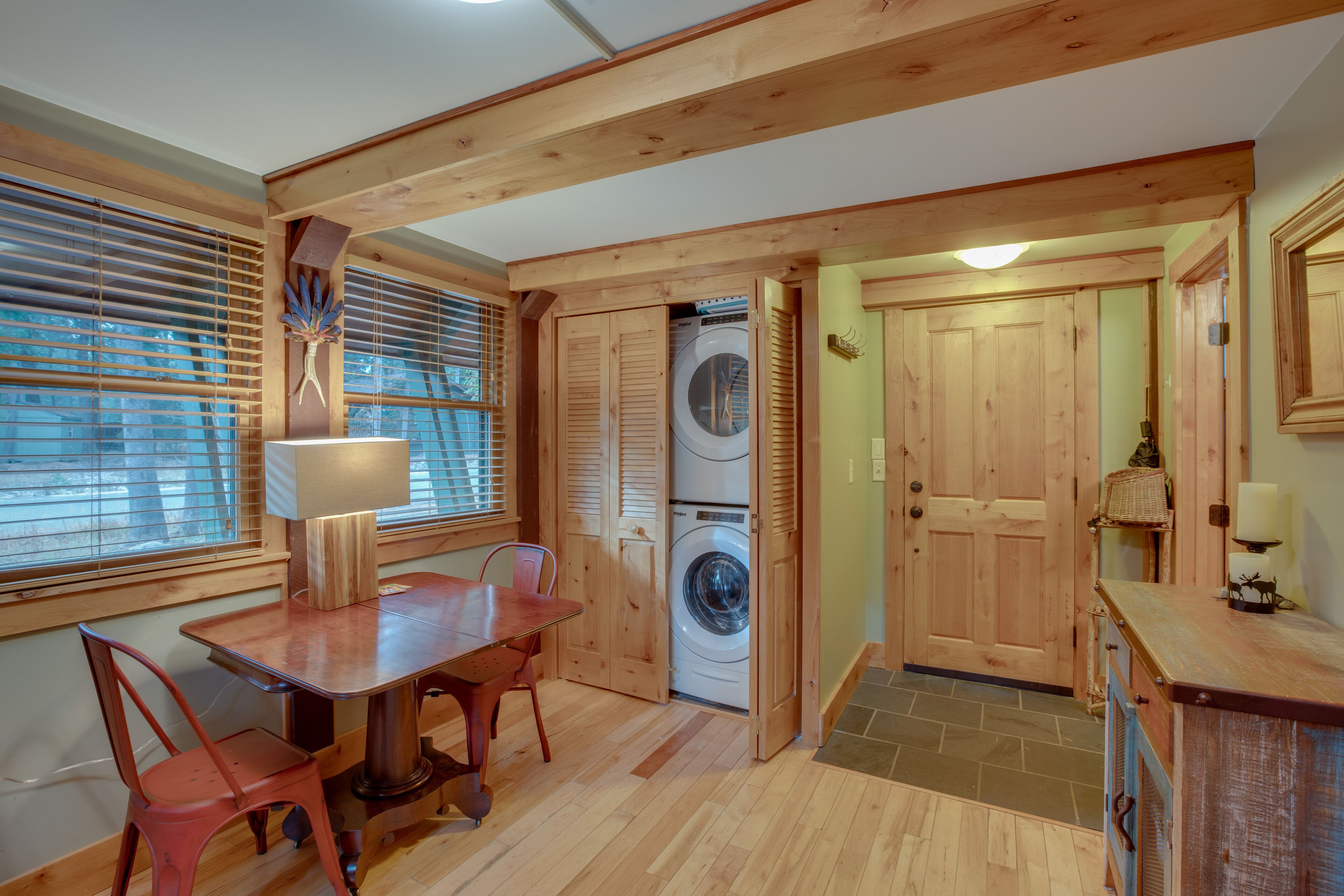 A compact room with a wooden table and chairs, a washing machine, and a door leading to another room.