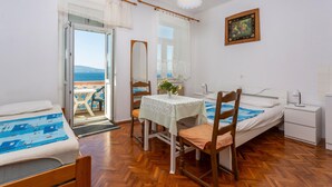 Una habitación con cama, una mesa con sillas, un escritorio y una silla. Hay una ventana con vista al mar.