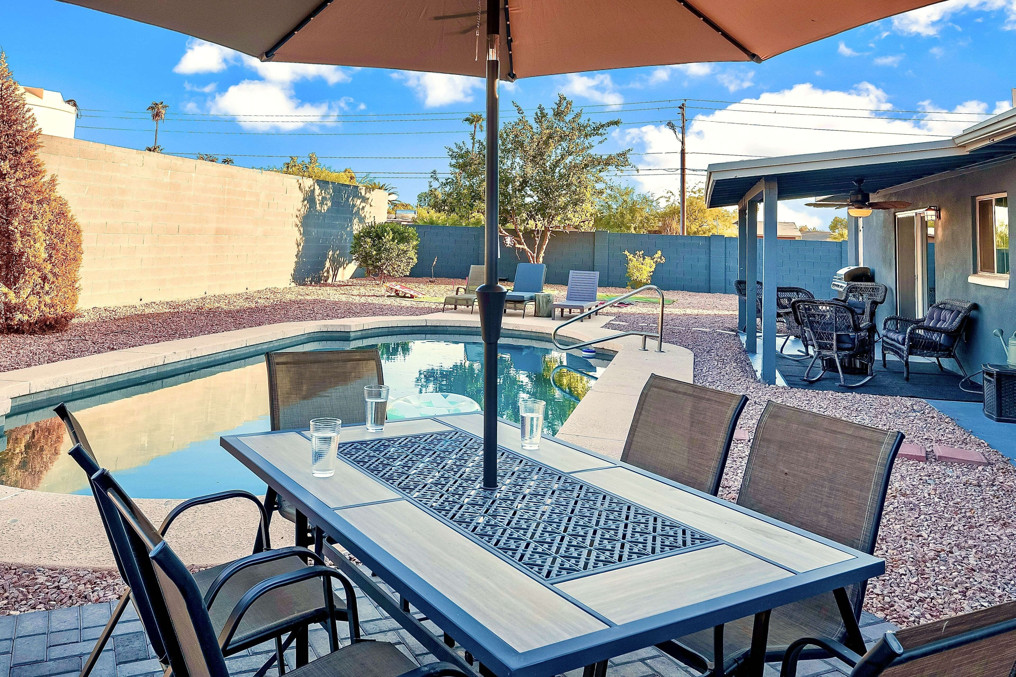 A backyard with a pool, outdoor seating, and a covered patio area.