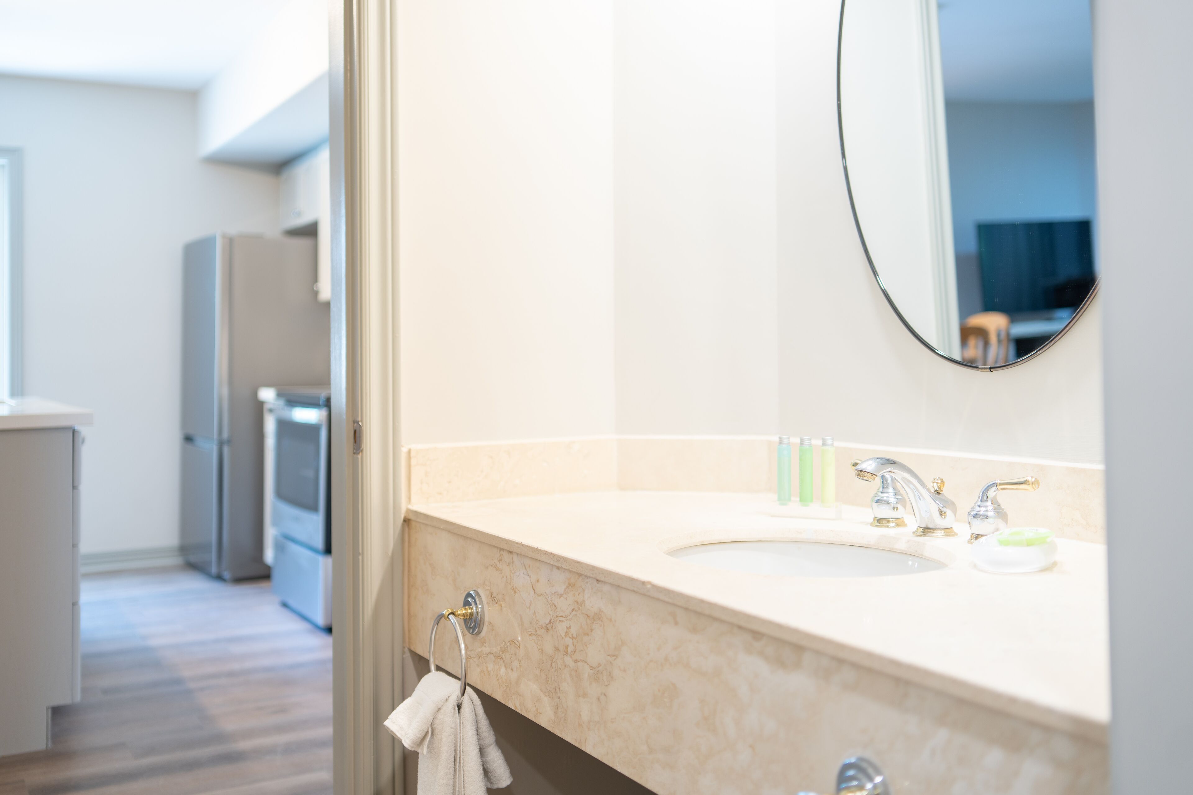 A modern bathroom with a marble sink, a mirror, and a towel rack.