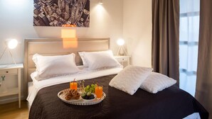 A neatly made bed with white linens, a tray of breakfast including croissants, fruit, and orange juice, and a cityscape painting above the bed. - Gorgeous home in Primosten (Primosten)