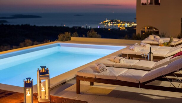 A poolside area with lounge chairs and a view of the sea at dusk. - Gorgeous home in Primosten (Primosten)