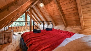 A cozy attic bedroom with wooden beams, a sloped ceiling, and a large window. - Cozy home in Gorkovec (Gorkovec)