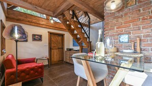 A cozy room with a red velvet sofa, a glass table with a bottle and glass, a wooden staircase, and a brick wall. - Cozy home in Gorkovec (Gorkovec)