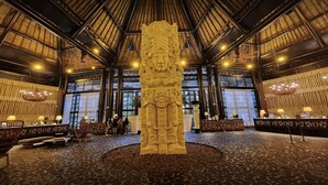 A lobby with a central stone sculpture, seating areas, and a high ceiling with skylights. - Cozy retreat, has something for everyone,property has golf course and lazy river (Las Jarretaderas)