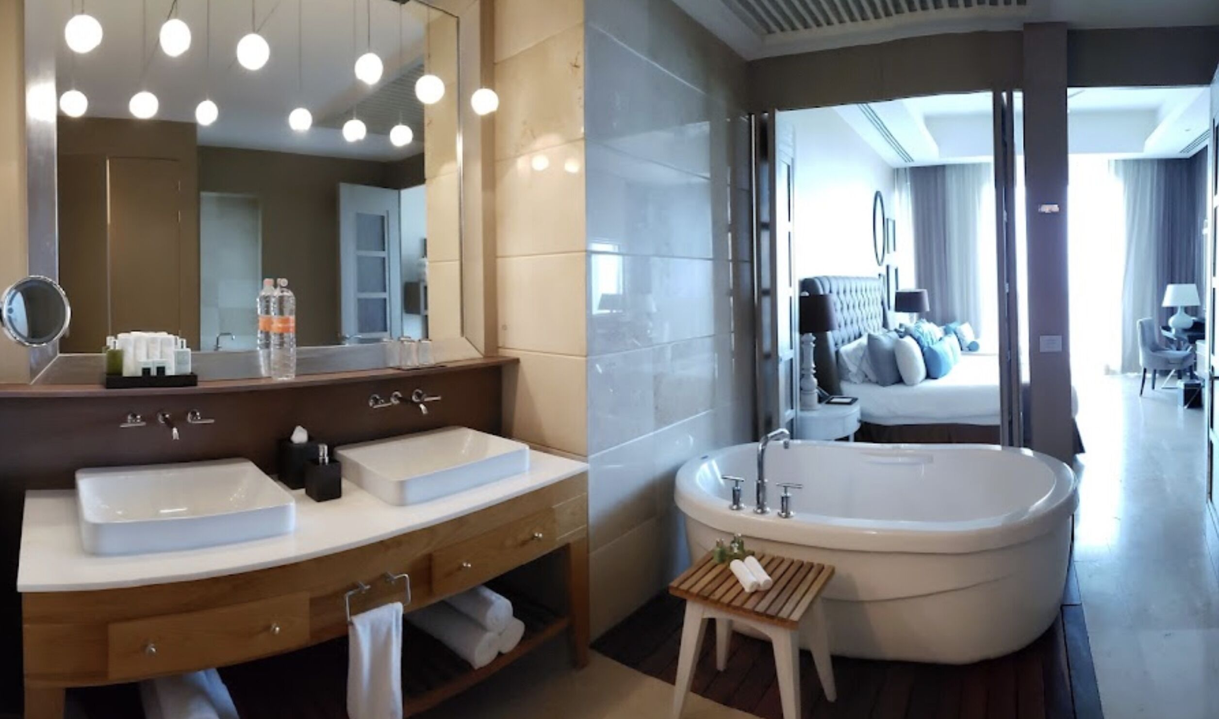 A modern bathroom with two sinks, a large mirror, and a freestanding bathtub.
